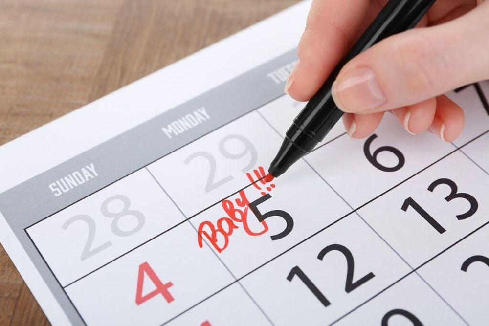 Người mẹ đang ghi chép, tượng trưng cho việc áp dụng công thức tính ngày dự sinh dựa trên chu kỳ kinh nguyệt cuối cùng.