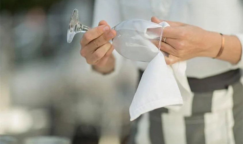 Người phụ nữ đang vệ sinh đồ dùng làm từ thủy tinh hữu cơ bằng khăn mềm, minh họa cách bảo quản các sản phẩm từ PMMA.